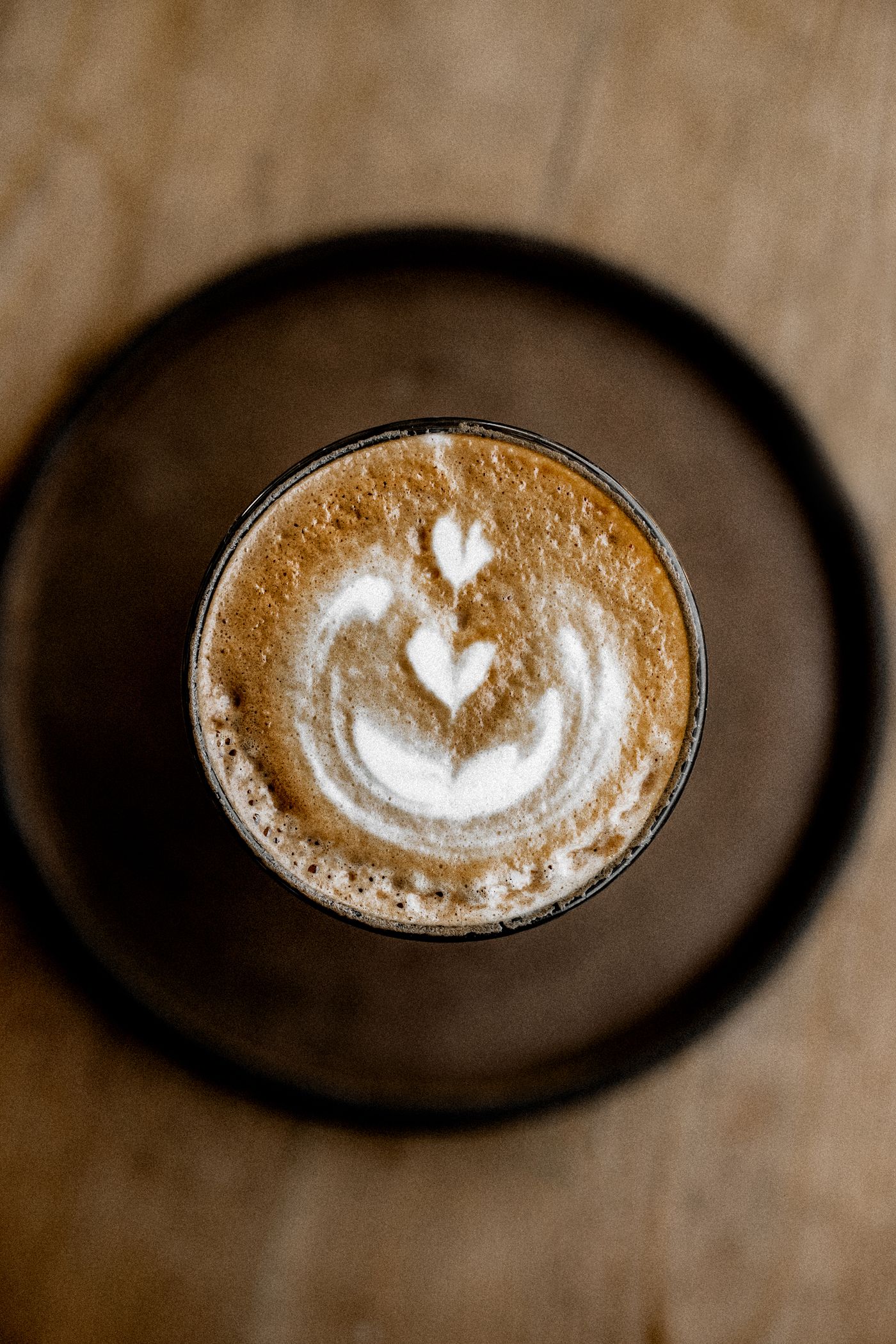 Heart-shaped latte art in a cappuccino, viewed from above on a wooden table