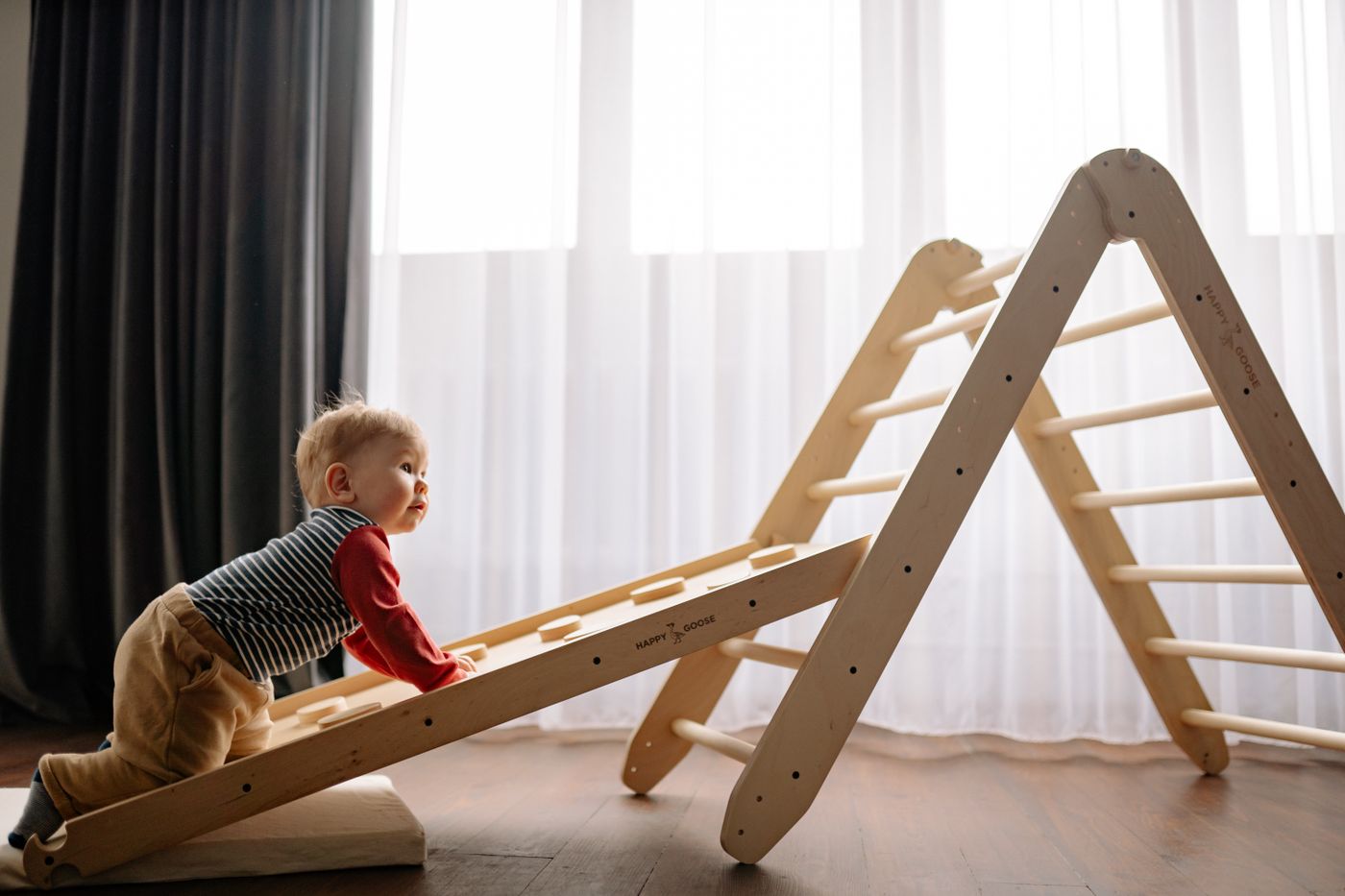 A toddler climbing a wooden play structure
